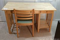 Front view of light finish desk with matching chair showing desk top and lower shelf.