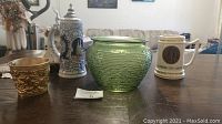 Overview of the lot showing the green vase, beer stein, college mug, and copper cup on the table