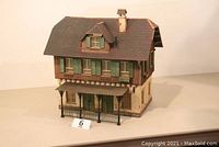 Front left angled view showing full two-story building with covered porch and chimney.