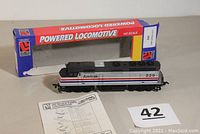 Photo showing Life-Like branded HO scale Amtrak #229 powered locomotive next to original blue and red box with 'Powered Locomotive' text and instruction sheet partially visible.