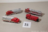 Three Santa Fe model locomotives and one red caboose are visible. The locomotives have red and silver colors with Santa Fe markings. The caboose is red with windows.