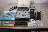 Top view of all bridge, pier, and trestle components laid out on a table. Includes boxed pier set, gray and black piers, truss components, and instruction sheet.