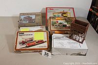 Full view of all items in the lot on table, showing multiple boxed kits and built pieces including a brown elevated structure