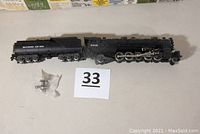 HO scale steam engine model 2-10-2 and 12-wheel tender laid out on a flat surface, includes small packet with extra wheels.