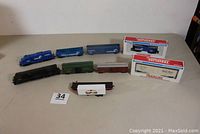 Nine HO scale railroad rolling stock items on a table including the Conrail diesel locomotive marked 7560, various box cars, hopper, caboose, and trailer.