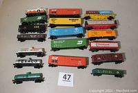 Lot of 18 HO scale rolling stock cars arranged on table showing various boxcars, tank cars, and other stock with couplers