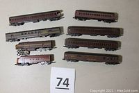 Photo with 6 Pennsylvania maroon and gold passenger cars viewed from above, showing elongated coach cars with black wheels and couplers.