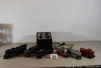 Full view of Lionel model train lot including steam engine, rolling stock, and transformer arranged stretched on a table.