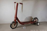 Front left angled view showing overall scooter structure including frame, front wheel, and training wheels.