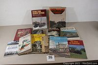 12 railroad books with various titles and conditions displayed on a white surface, visible front covers with titles and images.