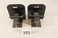 Pair of steel railroad bookends viewed from front showing the rail and spike mounted on flat plate stands, both have SR&RL markings.