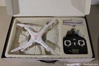 Syma X5C drone and remote control inside the original packaging and plastic insert with extra propellers.