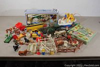 Overall layout of all barnyard toys including animals, tractor, trailer, fencing, mobile, and memory game on table.
