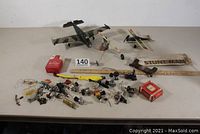 View of the entire lot spread out on table, showing three model planes, various small plane engines, tanks, propellers, and accessories including two red battery boxes and a wooden propeller.
