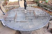 Overall view of multiple cast iron fence sections arranged on a stone table outdoors.