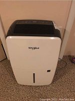 Front view of white Whirlpool dehumidifier with black top, showing overall design and Whirlpool logo.
