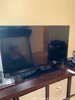 Samsung 38-inch HD television showing the full screen and stand on a dark wood cabinet.