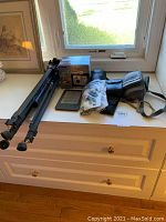 Toshiba PDR-M25 digital camera in box, tripod, Kindle, camera cases and Nikon/Canon cameras on display on table