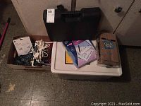Lot overview showing black toolbox, binders, lunch bags and envelopes, timer, and box containing extension cords.