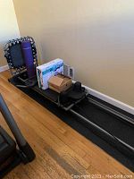 Full view of Pilates machine with exercise bands, yoga mat, boxed fitness ball, and boxed Bally fitness bands on wooden floor and black mat.