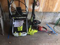 Overview of all items: power washer, hedge trimmers, chainsaw leaning against a wall.