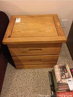 Front view of the wooden side table showing two drawers and the natural wood finish with scratches.
