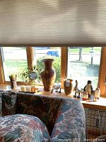 Photo of window ledge with large terracotta vase, several small vases, and three bird figurines.