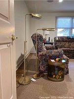 Two brass-tone reading floor lamps positioned next to floral upholstered furniture in a family room, showing height and structure.
