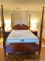 Full view of queen size four poster bed frame with mattress showing carved posts and wooden frame