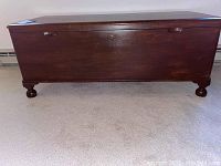 Front view of the solid wood blanket chest showing its walnut finish and lockable lid with side handles.