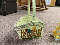 Wicker basket style birdhouse decorated with a painted fence and flowers