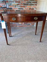Front view of the vintage wooden folding gaming table showing the rectangular shape, tapered legs, and central drawer with brass oval pull.