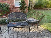 Full view of black wrought iron settee and side table on patio