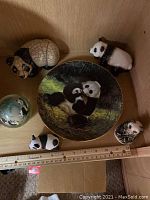Overview of collectible pandas around decorative plate with measuring ruler