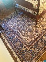 Full view of the multi-colored Oriental style area rug under a wooden bed frame showing the floral and geometric pattern.