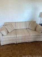 Light beige queen sleeper sofa with cushions, showing fabric texture and overall condition.