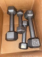 Five pairs of cast iron hexagonal hand weights in a cardboard box.