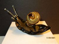Front right angled view of the glass snail figurine showing brown swirled shell and translucent brown body with clear antennae.