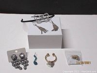 Image showing the full lot with various jewelry items arranged on a white block and surface, featuring earrings, headband, and pendant.