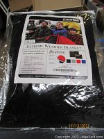 Packaged black Mambe Extreme Weather Blanket with label showing product features and branding.