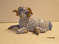 Front-right three-quarter view showing overall shape, blue fishnet pattern and gold-accented horns and hooves.