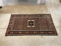 Top-down view of the full rug laid flat on concrete floor showing central medallion, border pattern and overall condition