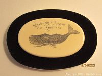 Close-up of interior lid plaque with etched whale and "Nantucket Sleigh Ride" inscription