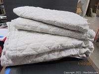 Stacked folded quilted king-size bedspread in oatmeal color