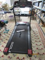 Full front view of treadmill assembled on patterned rug with control console and deck visible