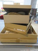 Stack of three Ugg boot boxes with boots partially visible inside.