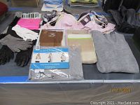 Photo showing assorted nylon stockings, packaged sleeper scarf, vintage gloves, scarves, and gray knit hooded sweater
