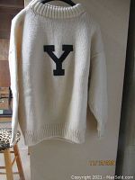 Front view of cream knitted pullover sweater with large black 'Y' letter on the front.