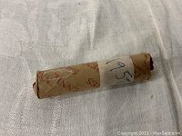 Photo showing the rolled bundle of 1957 wheat pennies wrapped in original coin paper, labeled with handwritten date.