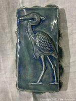 Front view of the ceramic wall tile showing the heron motif in blue glaze.